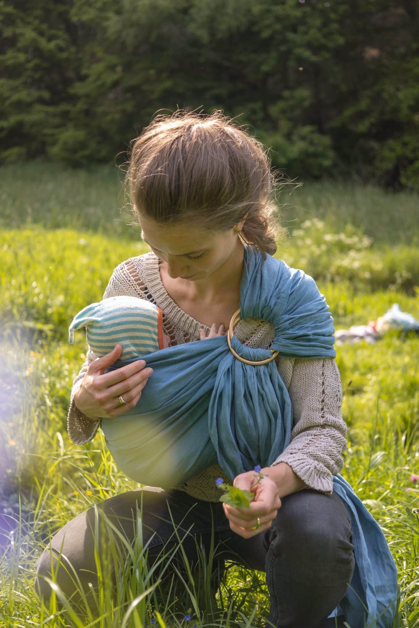 mother cuddeling a newborn baby in a babywearing sling