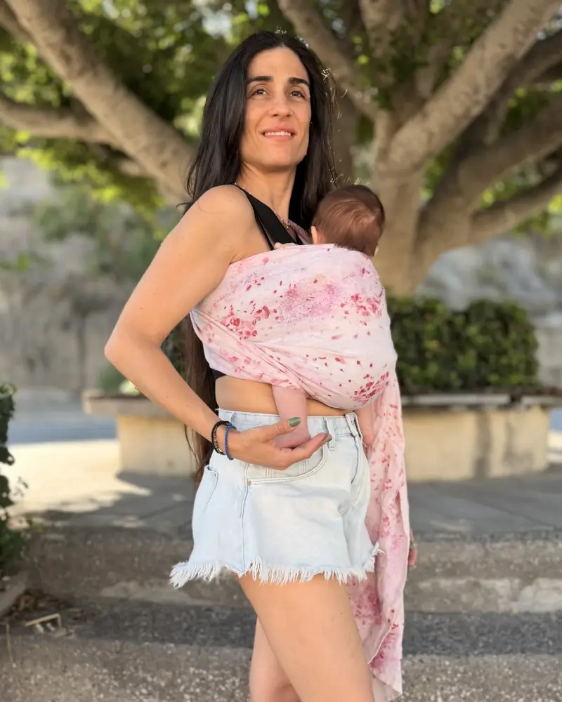 Mutter küsst ihr Baby im Mariblum Ringsling Kiss from a Rose mit rosafarbenem Blumenmuster.