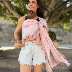 Frau trägt ihr Baby im rosafarbenen Mariblum Babytragetuch Kiss from a Rose als Ringsling für Neugeborene.