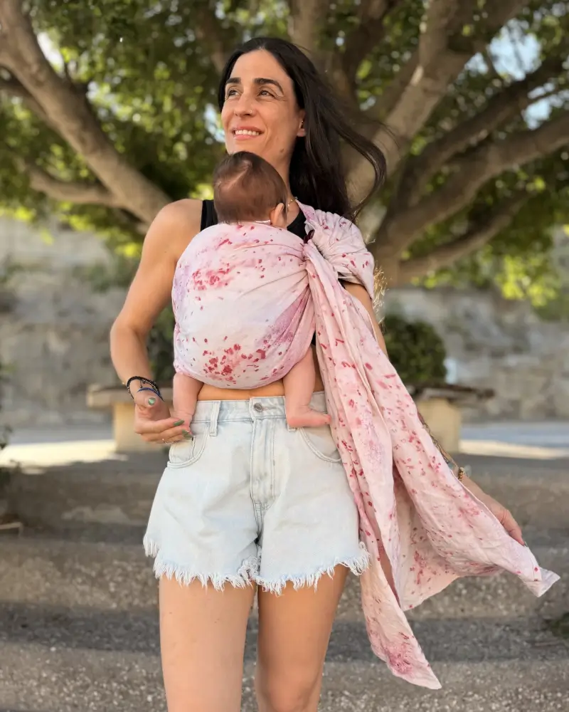 Frau trägt ihr Baby im rosafarbenen Mariblum Babytragetuch Kiss from a Rose als Ringsling für Neugeborene.