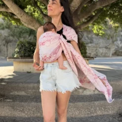 Frau trägt ihr Baby im Mariblum Babytragetuch Kiss from a Rose während eines Spaziergangs.