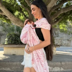 Mutter hält den Kopf ihres Babys im Mariblum Ringsling Kiss from a Rose mit rosafarbenem Blütenmuster.