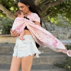 Mutter küsst ihr Baby im Mariblum Ringsling Kiss from a Rose mit rosafarbenem Blumenmuster.
