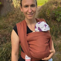 Un bébé endormi heureux dans une écharpe qui dort