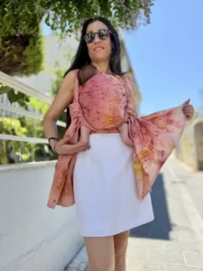Modische Mutter trägt ihr Baby im rosa mariblum Tragetuch aus Hanf als praktische Alternative zum Kinderwagen.