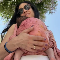 Nahaufnahme der ergonomischen Rückenhaltung eines Babys im mariblum Tragetuch aus Hanf mit Pflanzenfärbung.